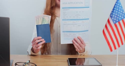 Woman Holds up Visa Application with Passport and Dollars