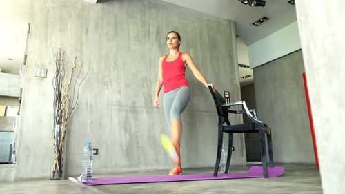 Woman working out using chair in living room