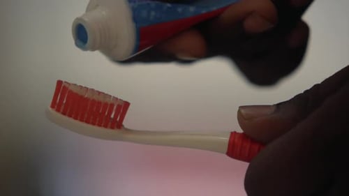 applying toothpaste on toothbrush bathroom