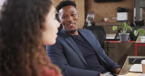 Two happy diverse creative colleagues in discussion in casual office, slow motion