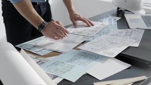 Architect Reviewing Construction Blueprint Plans on Table