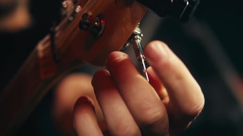 Young Musican Man Checking Strings of Acoustic Guitar Closeup Male Guitarist Tuning Sound of Musical