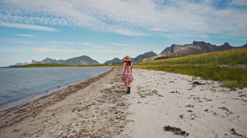 Woman Walks on Sandy Beach Near Mountains