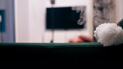 Close Up in an Apartment Cleaner in a Yellow Apron Does a Steam Cleaning of a Green Sofa with