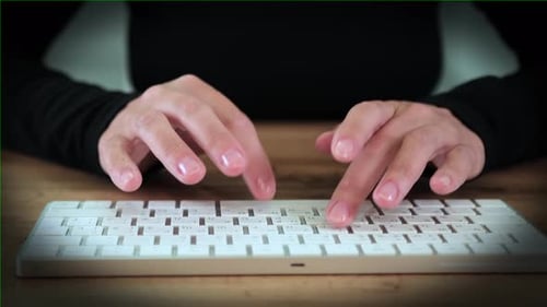 Nahaufnahme beim Tippen der Finger auf der Tastatur. Konzentrierte und entschlossene Arbeit einer Frau in schwarzer Kleidung
