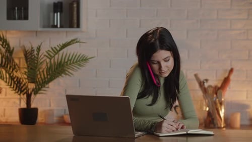 A Video Showing a Businesswoman in Her Home Office in Front of a Laptop Talking on the Phone with an