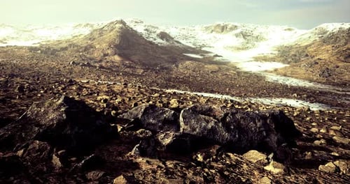 Vast Rocky Landscape with Snow Capped Mountains Under Clear Sky