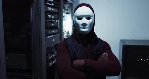 Un serveur, un pirate informatique et une personne masquée dans une salle de contrôle sombre constituent un risque pour la cybersécurité et le centre de données