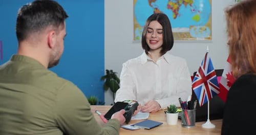 Happy Couple Buying Honeymoon Tickets at Travel Agency Man Using Smartphone to Pay