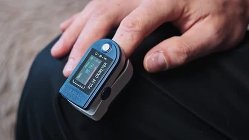 Pulsoximeter misst Puls und Sauerstoffsättigung an einem männlichen Finger in Nahaufnahme