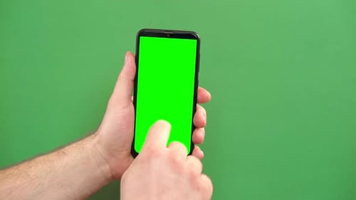 Smartphone für junge Männer zur Handbedienung mit grünem Bildschirm auf grünem Hintergrund, Gestenpaket, Männliches Berühren der Hand