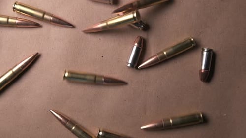 Images au
ralenti montrant des obus de fusil et des balles de pistolet tombant sur une table. Gros plan