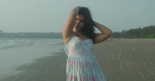 A woman is standing on a beach wearing a blue dress