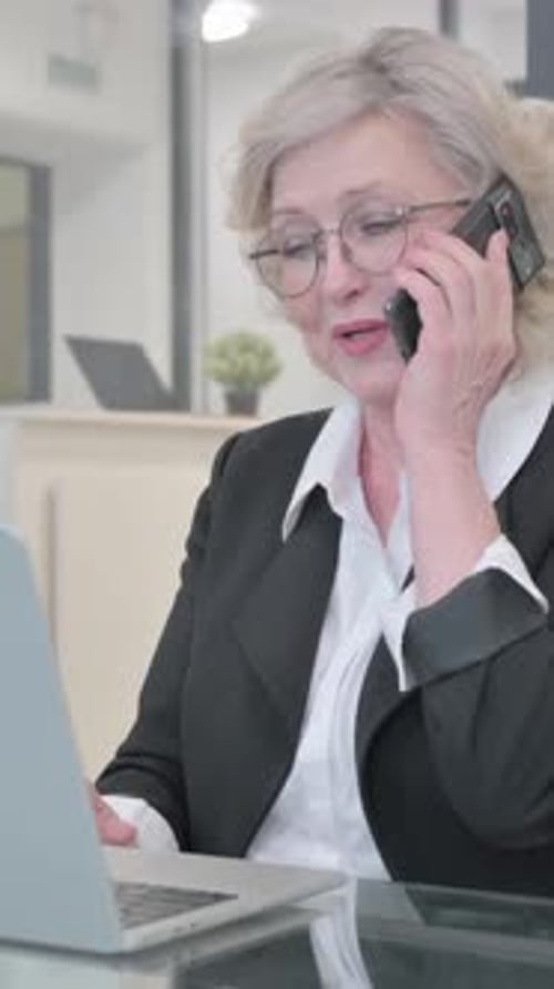 Mature Woman Working and Talking on Phone at Desk