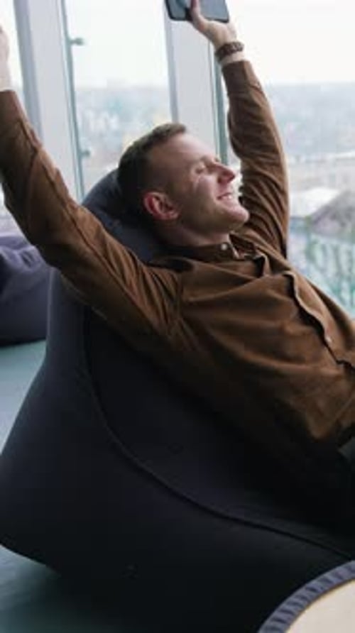 Man Relaxing in Beanbag Chair Holding Phone