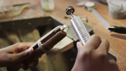 Biracial female worker shaping ring using handcraft tools in workshop in slow motion