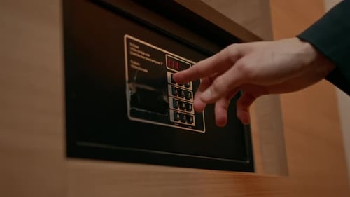Eine Hand gibt einen Code ein, um einen Safe oder Tresor in einem Hotelzimmer zu öffnen und zu verschließen. Diebstahl oder Aufbewahrung von Wertsachen