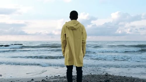 African american hipster stands at waters edge enjoying sunny autumn seascape