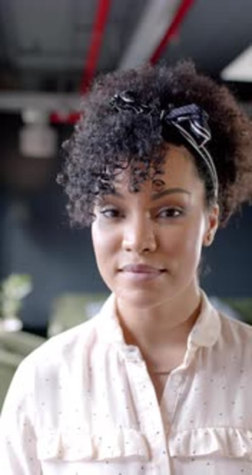 Vertical video of portrait of smiling african american businesswoman in office with copy space