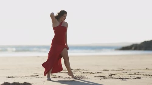 Graceful Woman in Red Dress Dancing on the Beach