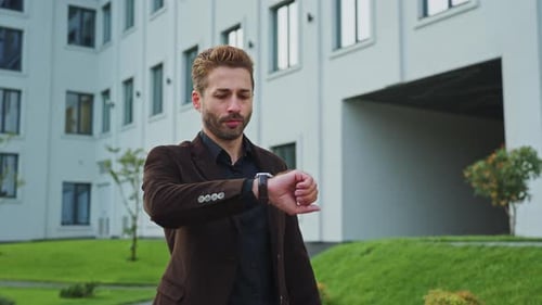 Man Checking Time While Waiting Outside a Modern Office in the Afternoon