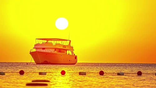 Timelapse of sunrise above a yacht moored at an anchor moving in the sea.