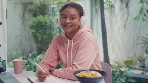 Woman with Headphones Smiling at Desk Indoors