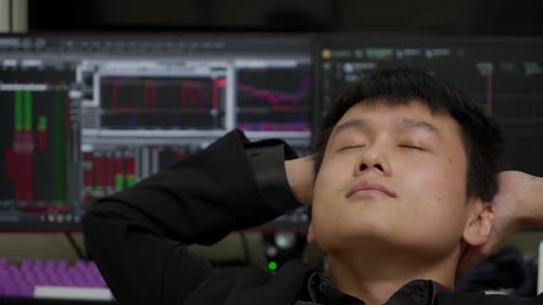 Asian man relaxes with stock market in background