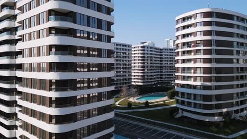 Drohnenaufnahme einer modernen Wohngebäudefassade mit braunen Paneelen und weißen Balkonen