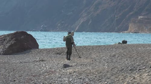 Beach MetalDetector Treasure Man Searches Seashore with Detector During the Day for Valuables