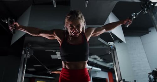 Muscular Woman Bodybuilder is Training in the Gym