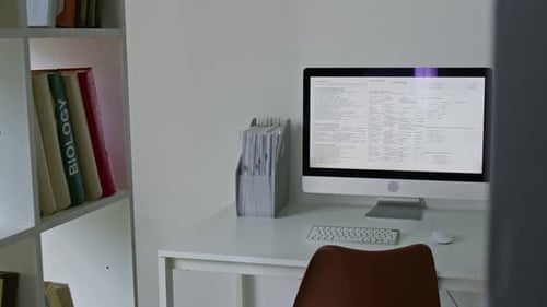 Desk with computer, books, lamp, and white walls