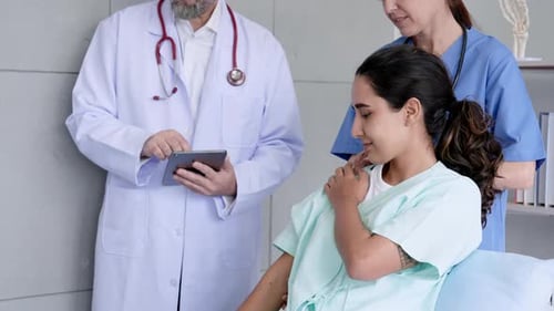 Doctor and Nurse Consulting with Patient in Hospital