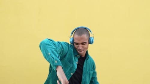 Man Dancing with Headphones Against Yellow Background