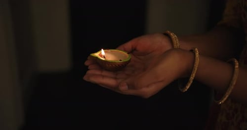 Hands Holding Lit Diwali Diya Lamp in Darkness