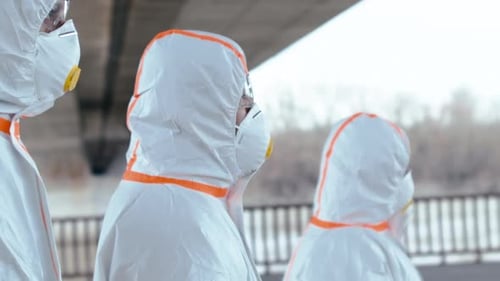 Médecins portant des combinaisons de protection et des respirateurs marchant à l'extérieur, concept de coronavirus