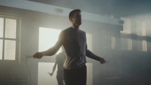 Athletic Adults Jumping Rope in Smoky Gym