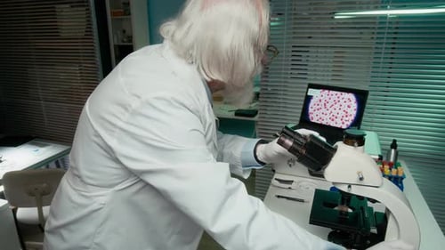 Scientist Looks Through Microscope in Lab