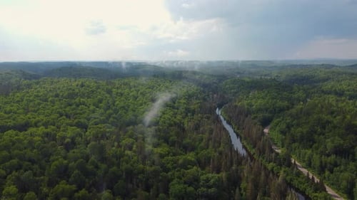 Thin Foggy Clouds Over Densely Forest With River Stream Near Muskoka In Ontario, Canada. Aerial Shot
