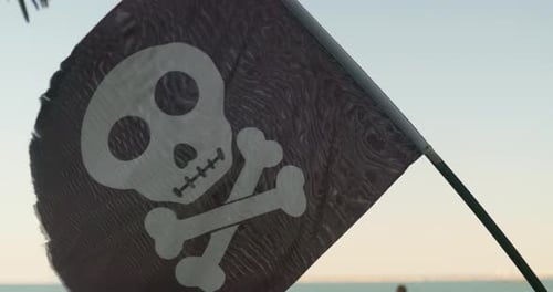 Waving Pirate Flag with Skull and Crossbones on Beach