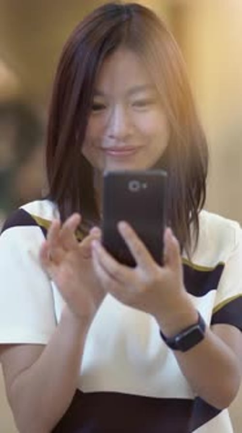 Woman Smiling and Using a Phone in City