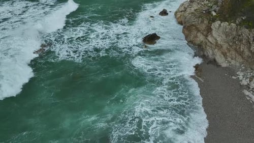 Aerial Video of Coastal Rocks Surrounded By Rough Sea Waves Creating Patterns of White Foam and