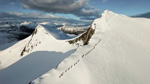 Massive group of people climbing up snowy mountain for skiing, aerial view
