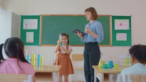 Adorable student learn with teacher in classroom at elementary school.