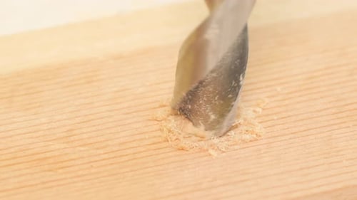 Horizontal Video of a Wet Drill Making Holes in a Wooden Surface with Shavings