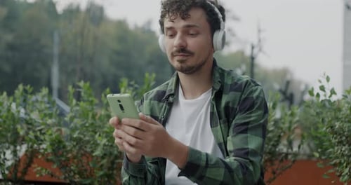 Man Using Phone With Headphones in City