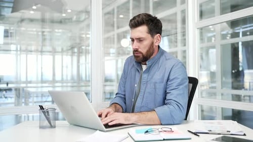 Businessman froze while working on laptop sitting at workplace in a modern business office. Upset