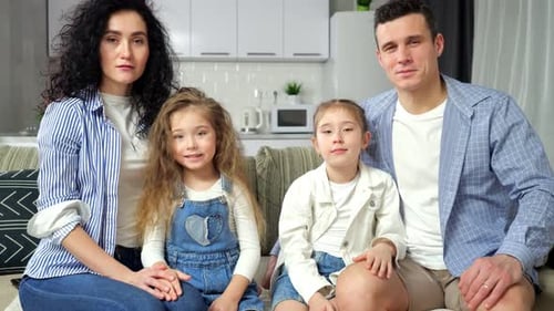 Happy Family Smiling Together on Couch at Home