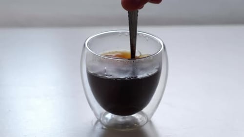 Adding One Teaspoon Of Coffee Powder Into Double Wall Glass And Stir To Dissolve. close up