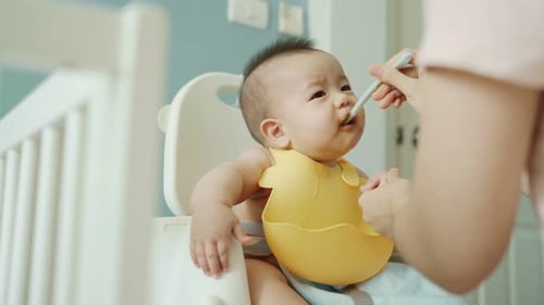 Adorable Infant Eating Food in High Chair